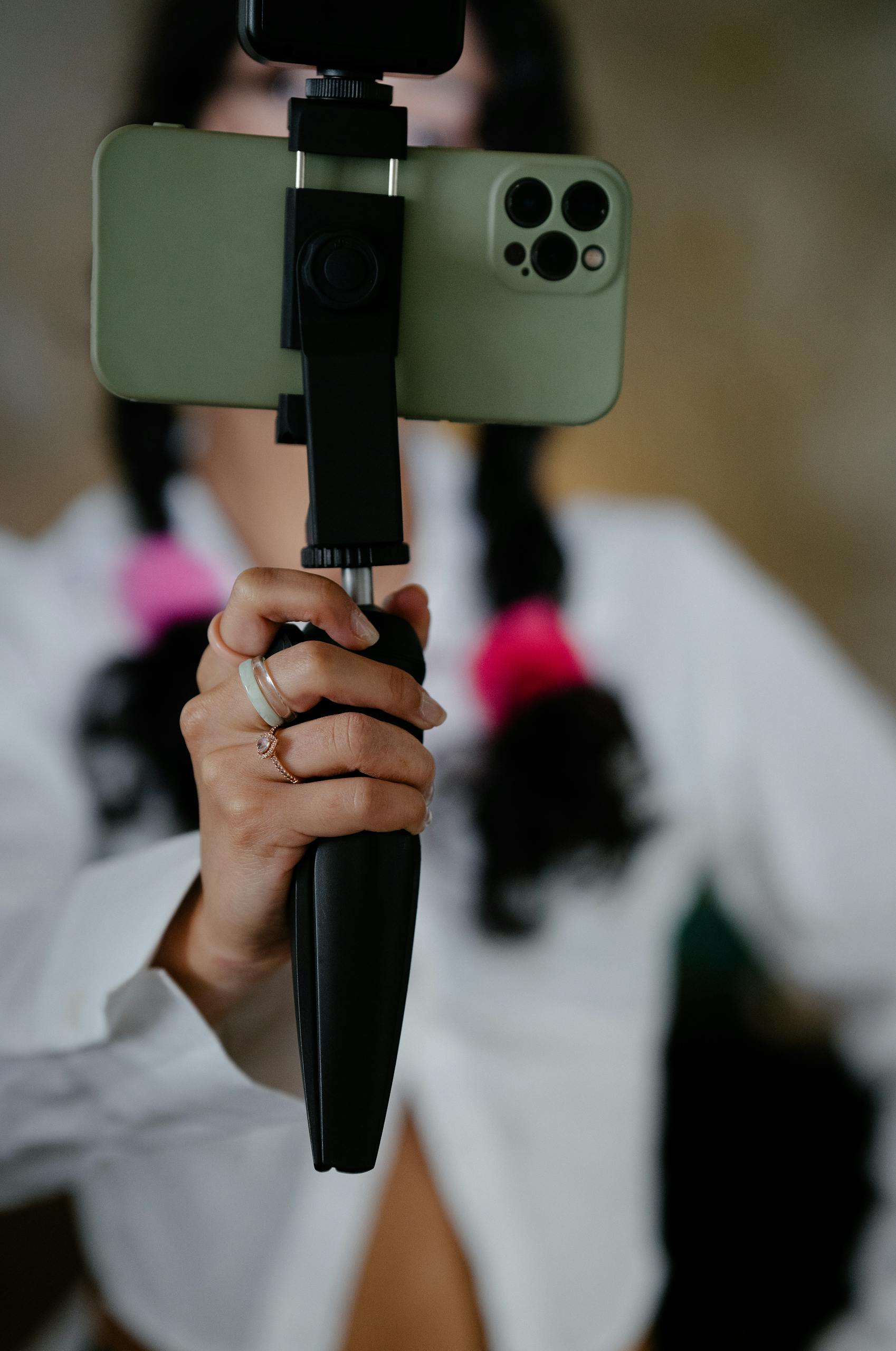 Close-up of a woman's hand holding a smartphone mounted on a tripod, focusing on modern technology.